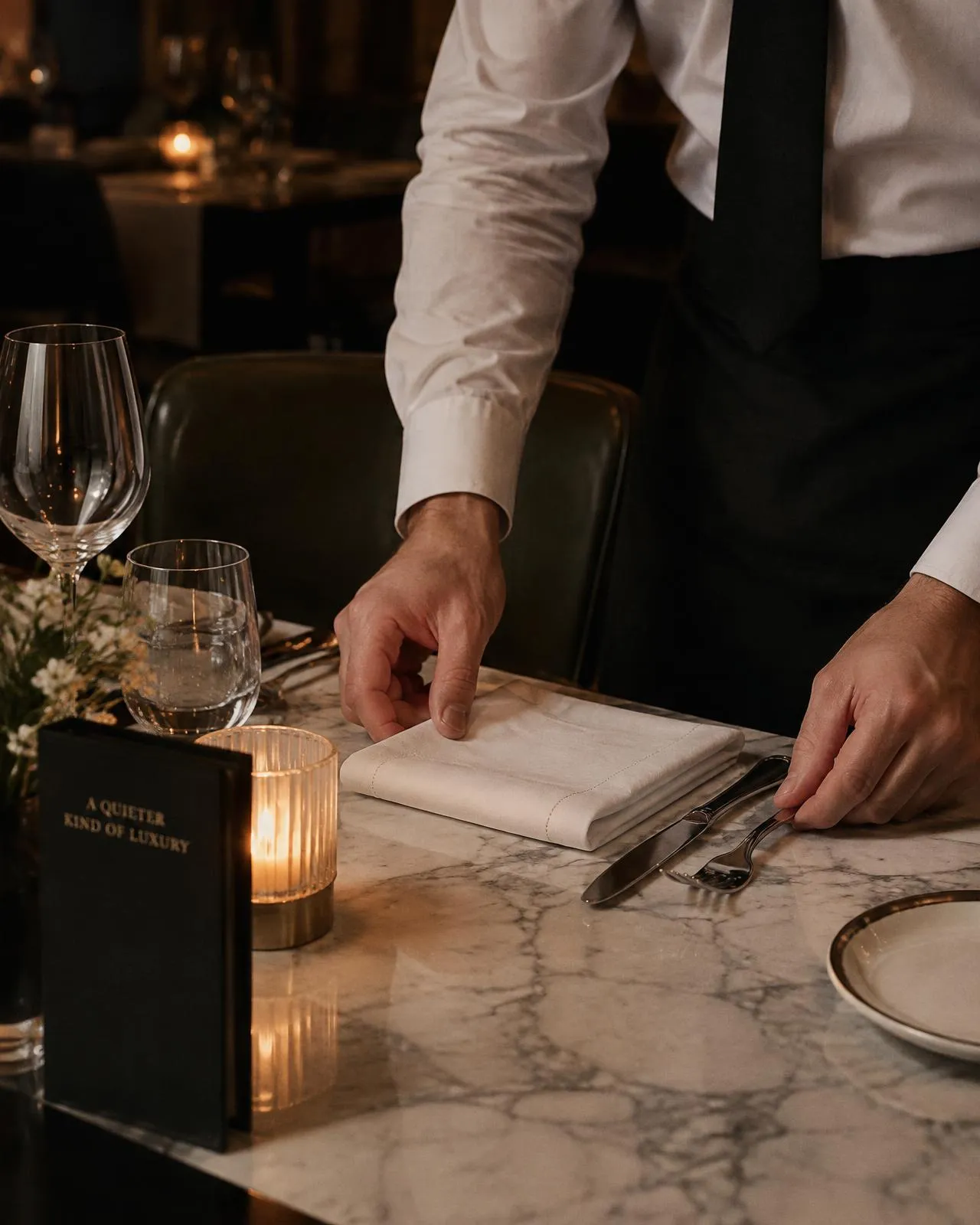 An Elite waiter setting a candlelit table before service